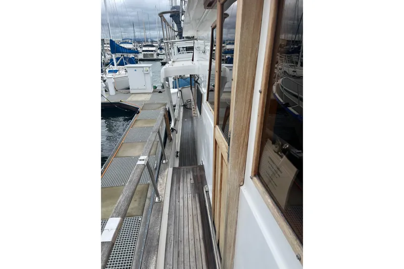 Slide: The Image of 1986 Sea Ranger 47 Pilothouse yacht docked at marina, showcasing wooden deck and cabin. - 32