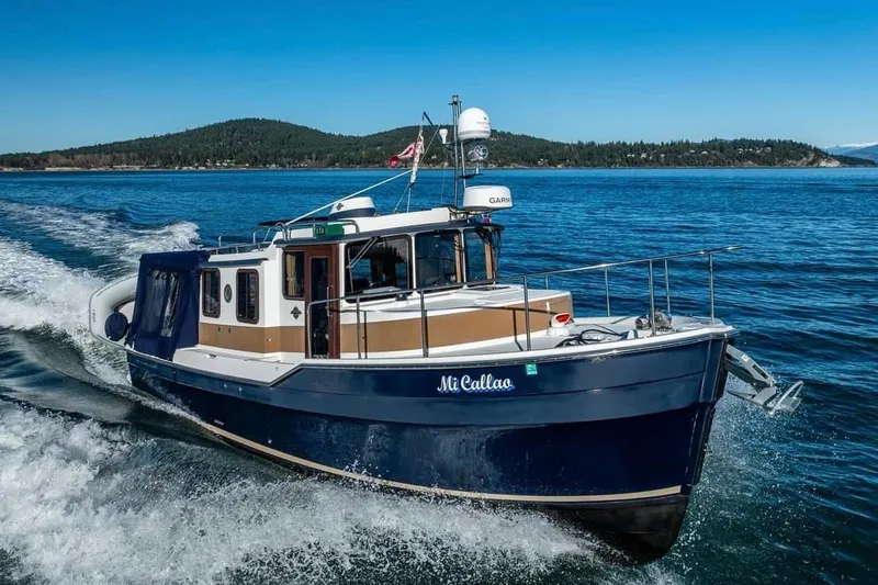 Slide: The Image of 2015 Ranger Tugs R-31S cruising on open water with scenic island backdrop. - 1