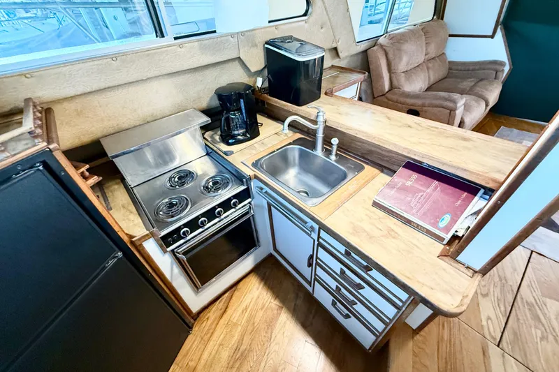 Slide: The Image of 1982 Sea Ray 355T Trawler kitchen with stove, sink, and cozy seating area. - 15