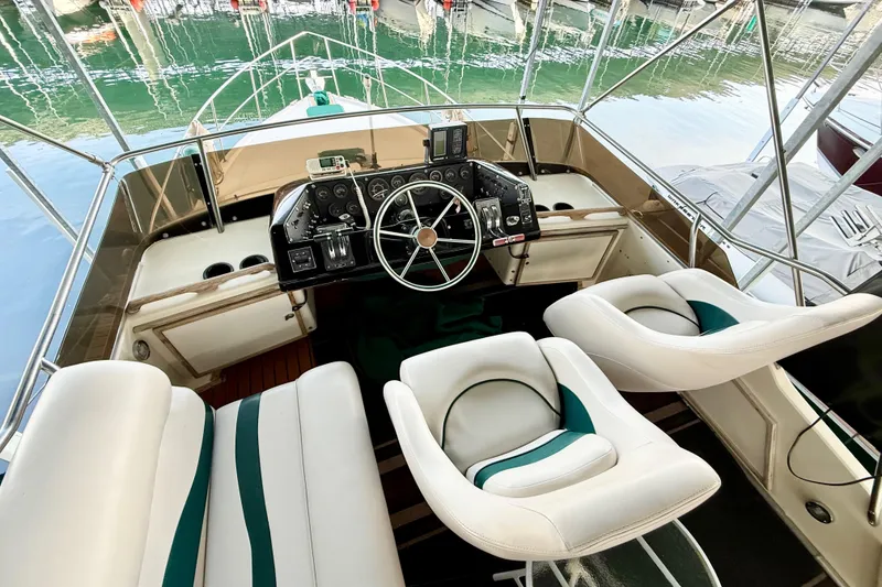 Slide: The Image of 1982 Sea Ray 355T Trawler cockpit with steering wheel and white seating. - 22