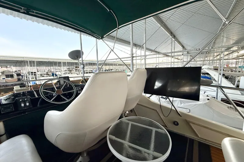 Slide: The Image of 1982 Sea Ray 355T Trawler helm with white seats, steering wheel, and marina view. - 24