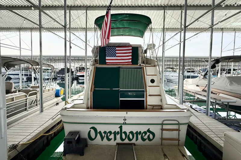 Slide: The Image of 1982 Sea Ray 355T Trawler docked, displaying an American flag and "Overbored" name. - 27
