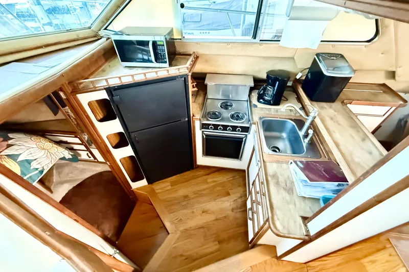 Slide: The Image of 1982 Sea Ray 355T Trawler kitchen with stove, sink, fridge, and microwave. - 5