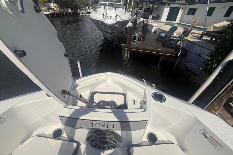 Slide: The Image of 2024 Yamaha Boats 255 FSH Sport H docked, showcasing open storage compartment and sleek design. - 14