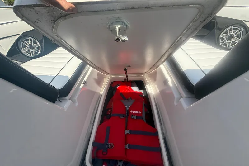 Slide: The Image of 2024 Yamaha Boats 255 FSH Sport H storage compartment with red life jacket. - 17