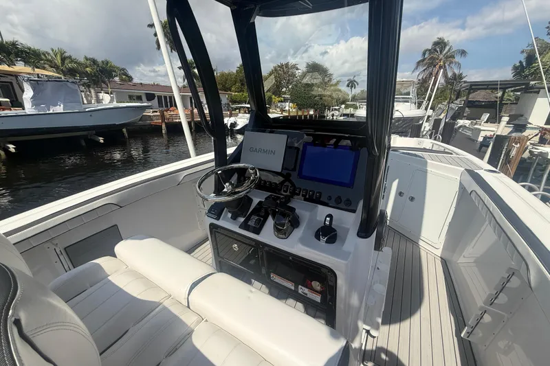 Slide: The Image of 2024 Yamaha Boats 255 FSH Sport H cockpit with Garmin navigation, docked by waterfront homes. - 4