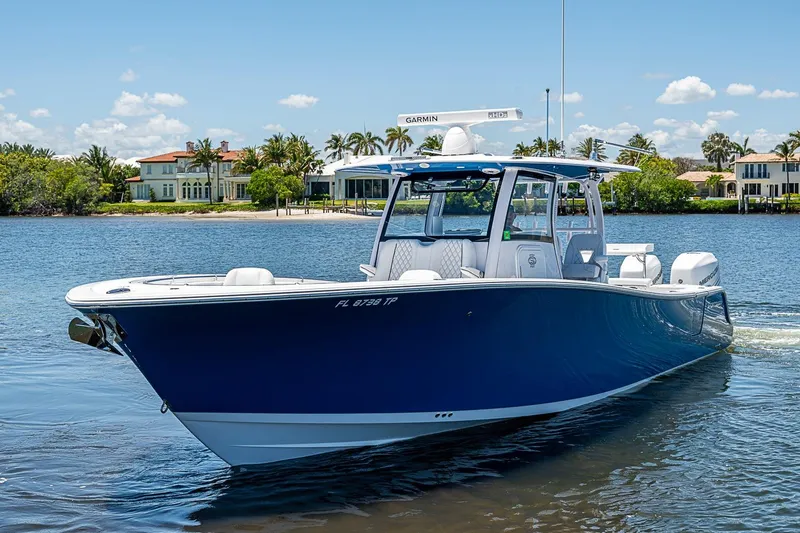 The Image of 2023 Sportsman Open 352 Center Console boat cruising on a sunny day near waterfront homes. - 0