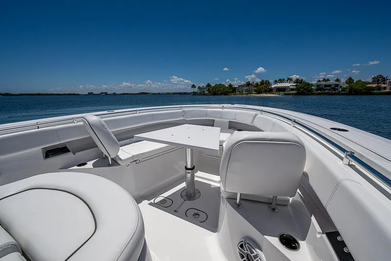 Slide: The Image of 2023 Sportsman Open 352 Center Console boat interior with seating and table on a sunny day. - 10