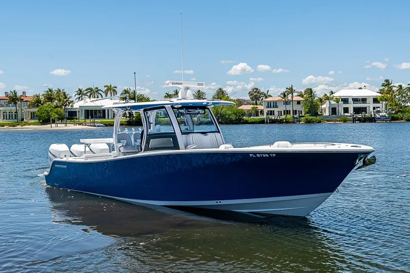 Slide: The Image of 2023 Sportsman Open 352 Center Console boat on calm water, with luxury homes in the background. - 2