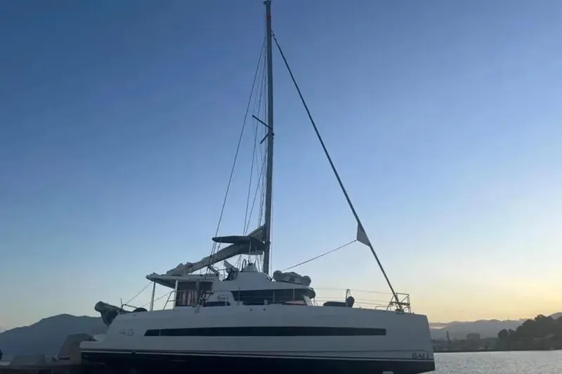 Slide: The Image of 2019 Bali 4.3 catamaran at sunset, docked with mountains in the background. - 2