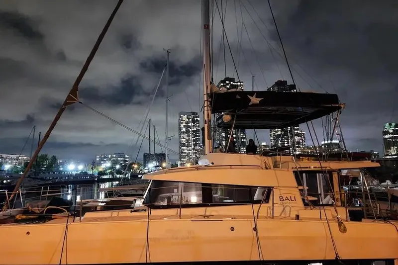 Slide: The Image of 2019 Bali 4.3 catamaran docked at night with city skyline backdrop. - 4