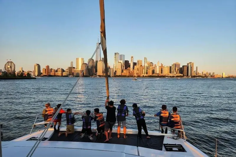 Slide: The Image of Children on a Bali 4.3 catamaran enjoy a city skyline view at sunset, 2019. - 5