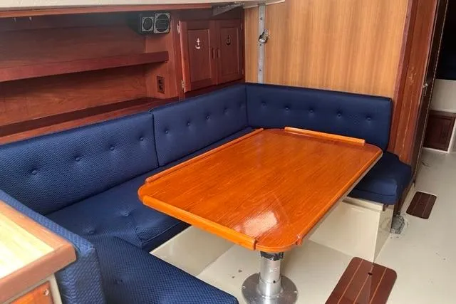 Slide: The Image of 1982 Catalina 38 sailboat interior with blue cushioned seating and polished wooden table. - 11