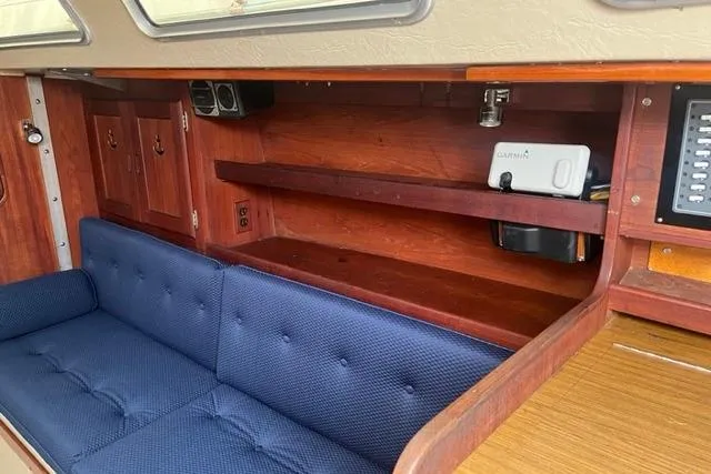 Slide: The Image of Interior of 1982 Catalina 38 sailboat with blue cushioned seating and wooden shelves. - 13