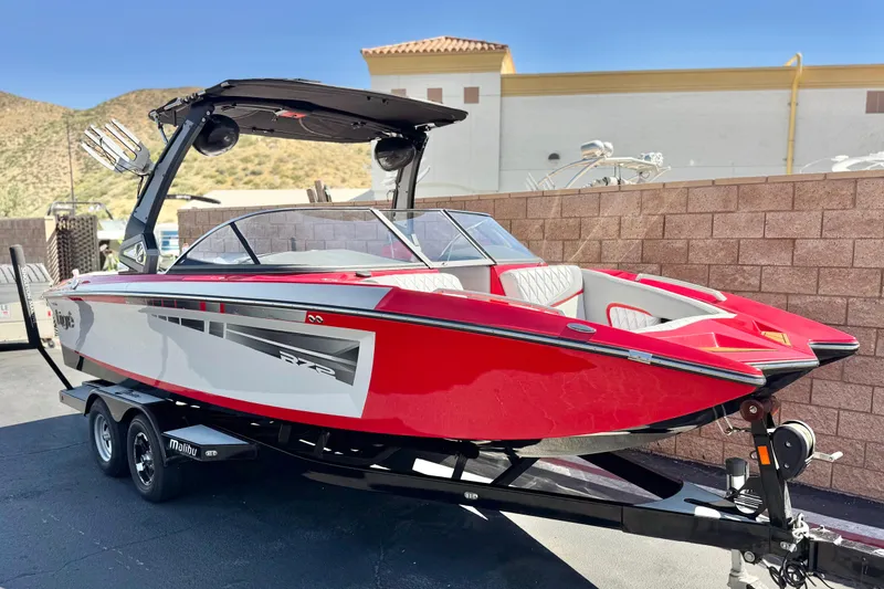 Slide: The Image of 2017 Tigé RZ2 boat in vibrant red on a trailer, parked outdoors. - 1