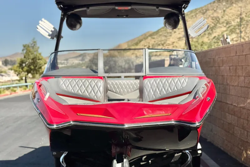Slide: The Image of 2017 Tigé RZ2 boat with red and gray interior, parked outdoors. - 2