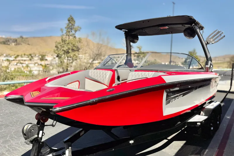 Slide: The Image of 2017 Tigé RZ2 boat in vibrant red, parked on a trailer, with scenic background. - 3