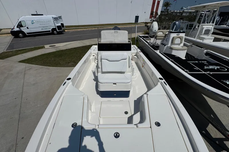 Slide: The Image of 2025 Skeeter SX221 boat with white seating, parked outdoors near a service van. - 14