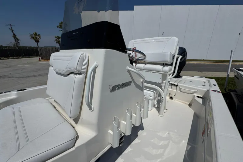 Slide: The Image of 2025 Skeeter SX221 boat interior with white seating and console, parked outdoors. - 15