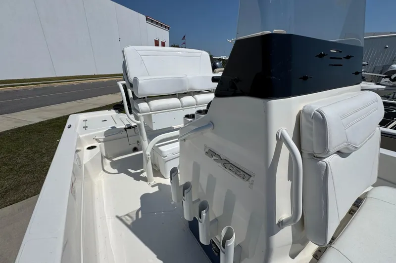 Slide: The Image of 2025 Skeeter SX221 boat interior with white seating and console, docked outdoors. - 16
