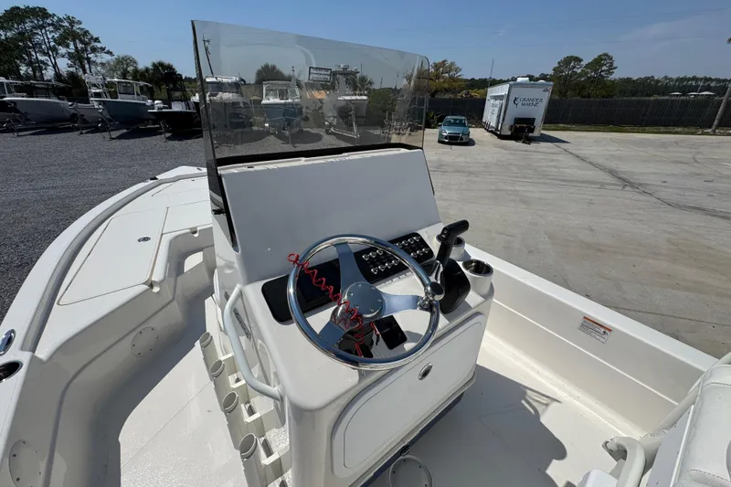 Slide: The Image of 2025 Skeeter SX221 boat console with steering wheel and controls in a marina setting. - 18