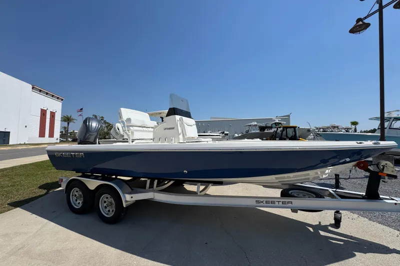 Slide: The Image of 2025 Skeeter SX221 boat on trailer, parked outdoors under clear blue sky. - 3