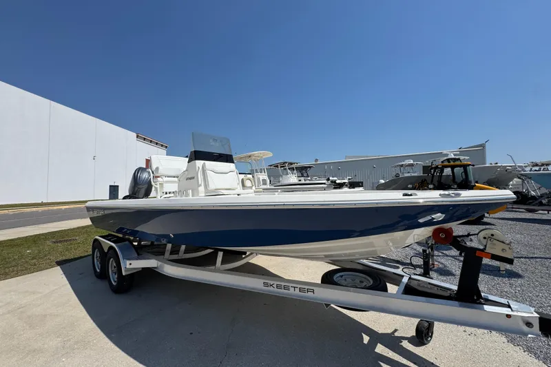 Slide: The Image of 2025 Skeeter SX221 boat on trailer, parked outdoors under clear blue sky. - 4