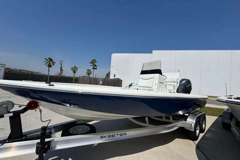 Slide: The Image of 2025 Skeeter SX221 boat on trailer, parked outdoors under clear blue sky. - 8