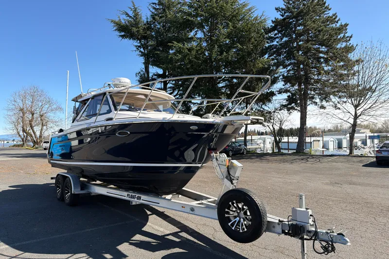 The Image of 2023 Cutwater C-248 Coupe boat on trailer, parked outdoors with trees in background. - 0