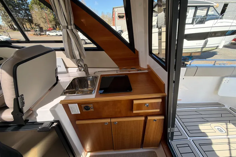 Slide: The Image of 2023 Cutwater C-248 Coupe interior with kitchenette, featuring sink, stove, and wooden cabinetry. - 20