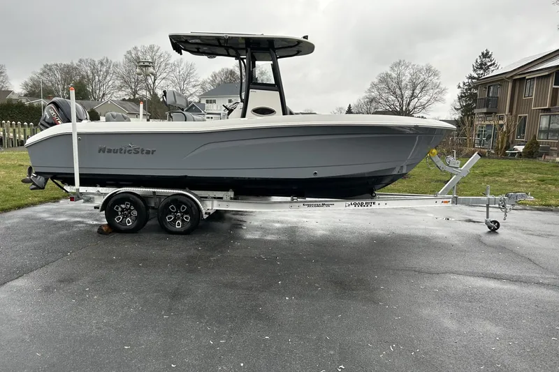 The Image of 2023 NauticStar 24 Legacy boat on trailer, parked outdoors on a cloudy day. - 0