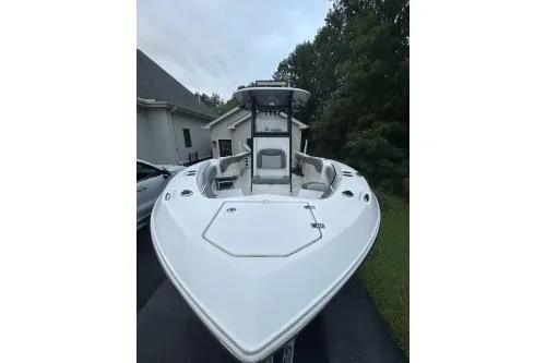 Slide: The Image of 2023 NauticStar 24 Legacy boat, sleek design, parked outdoors near a house. - 2