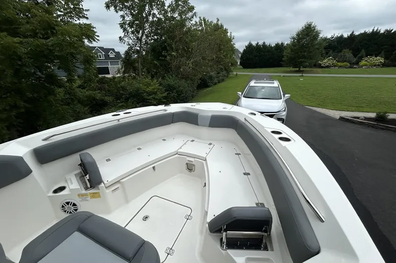 Slide: The Image of 2023 NauticStar 24 Legacy boat with spacious seating, parked near a white car in a driveway. - 3