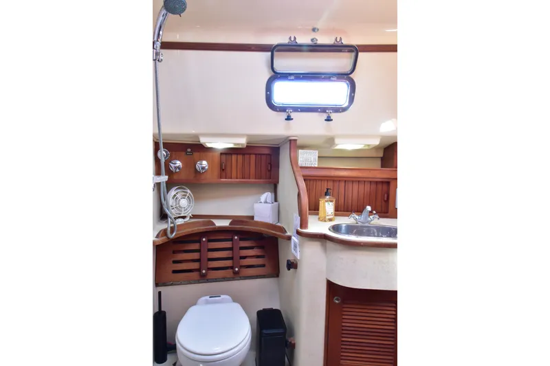 Slide: The Image of 1999 Island Packet 380 yacht bathroom with sink, toilet, and wooden cabinetry. - 20