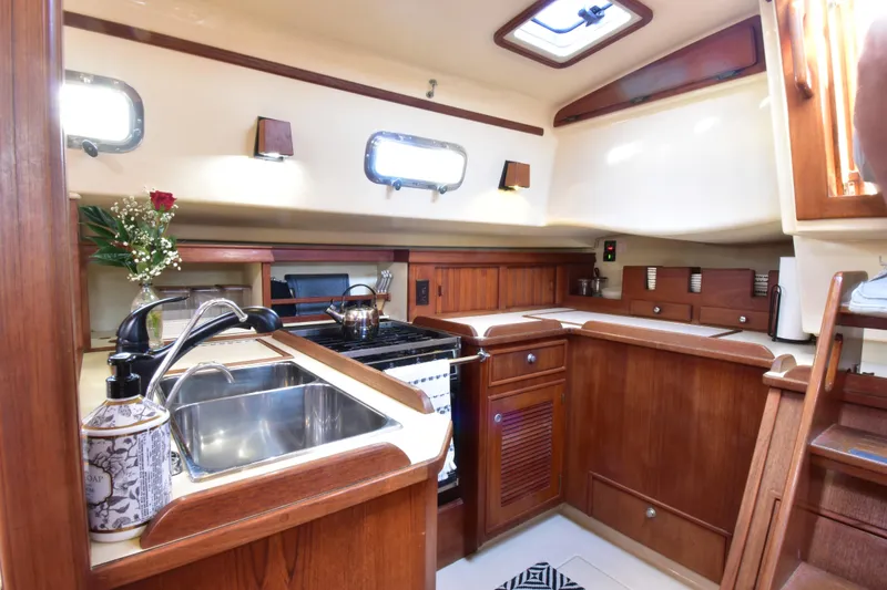 Slide: The Image of Interior of 1999 Island Packet 380 sailboat with wooden cabinetry and modern kitchen amenities. - 25
