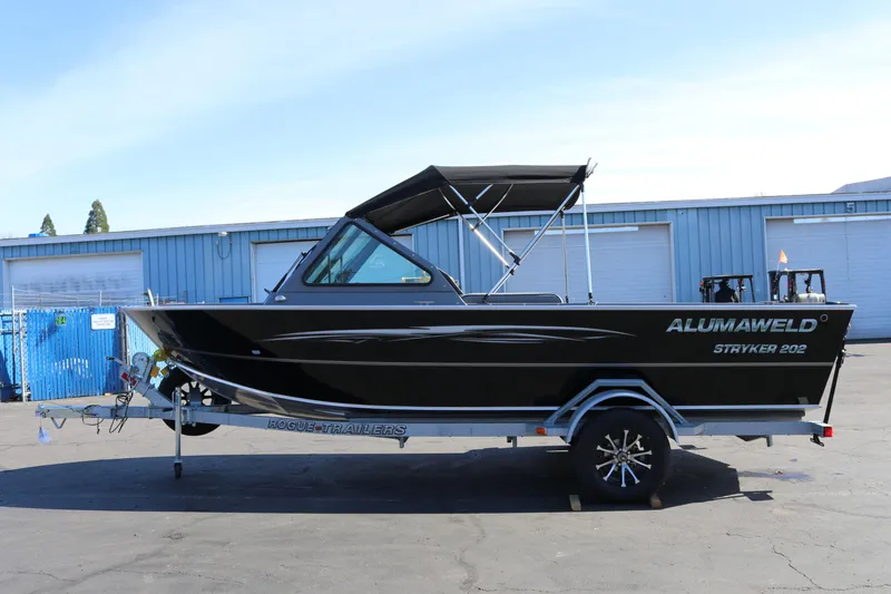 Slide: The Image of 2026 Alumaweld Stryker 202 boat on trailer, parked outdoors near blue building. - 4