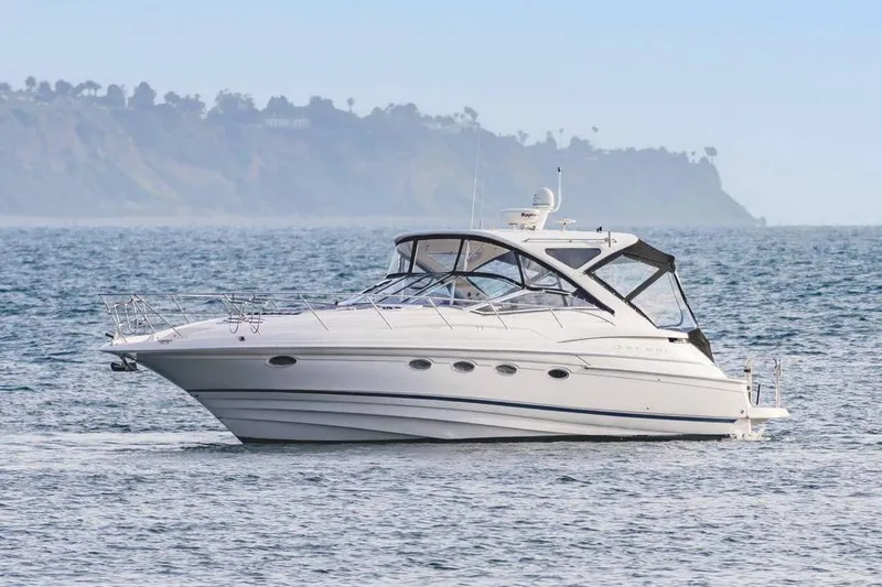 The Image of 2010 Regal Commodore 4460 yacht cruising on open water with scenic coastline backdrop. - 1