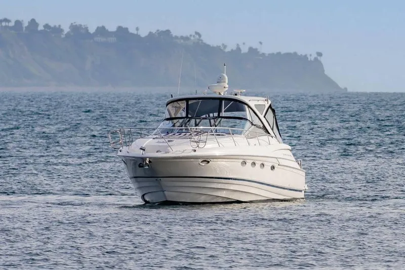 Slide: The Image of 2010 Regal Commodore 4460 yacht cruising on open water with scenic coastline backdrop. - 3
