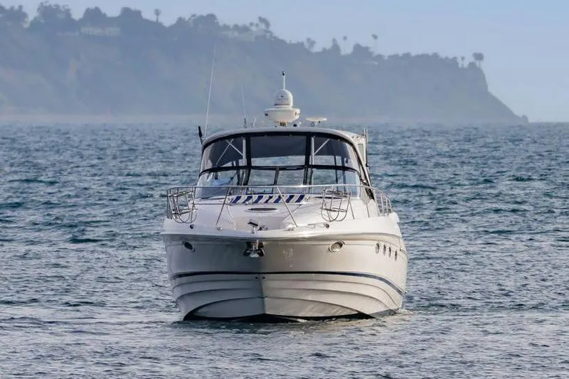 Slide: The Image of 2010 Regal Commodore 4460 yacht cruising on open water with scenic coastline backdrop. - 4