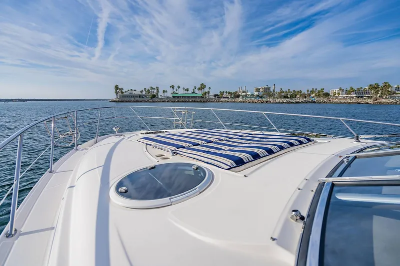 Slide: The Image of 2010 Regal Commodore 4460 yacht with striped sunbed, cruising near coastal cityscape. - 42