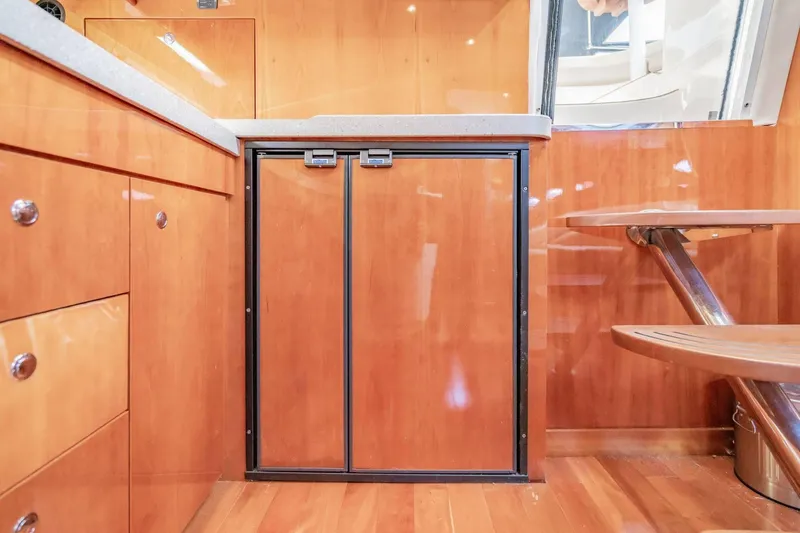 Slide: The Image of Interior of 2010 Regal Commodore 4460 yacht with wooden cabinetry and compact fridge. - 53