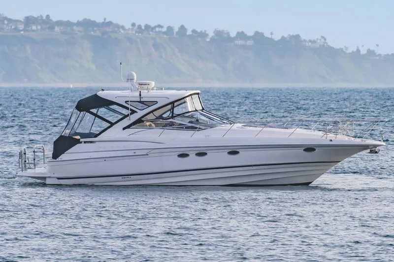 Slide: The Image of 2010 Regal Commodore 4460 yacht cruising on the ocean with scenic coastline backdrop. - 6