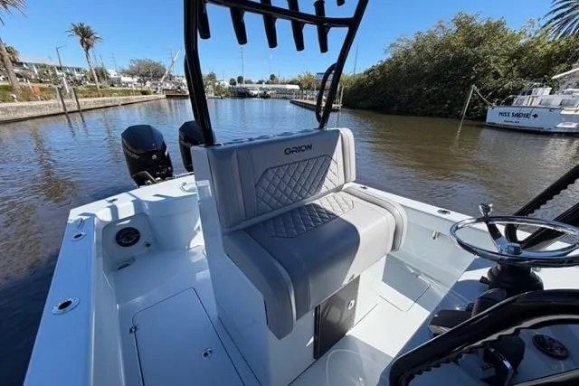 Slide: The Image of Orion 29 boat interior, 2026 model, featuring sleek seating and steering on a sunny waterway. - 9