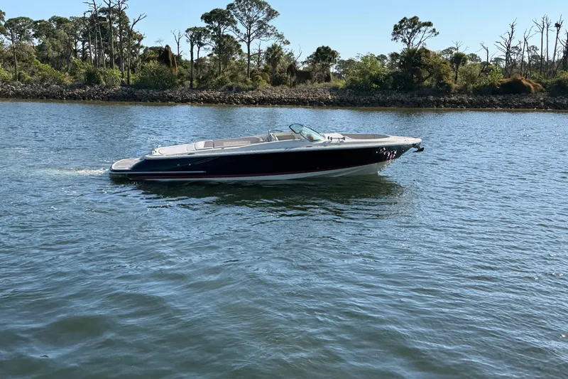 Slide: The Image of 2019 Chris-Craft Launch 30 boat cruising on a serene lake with lush greenery. - 2