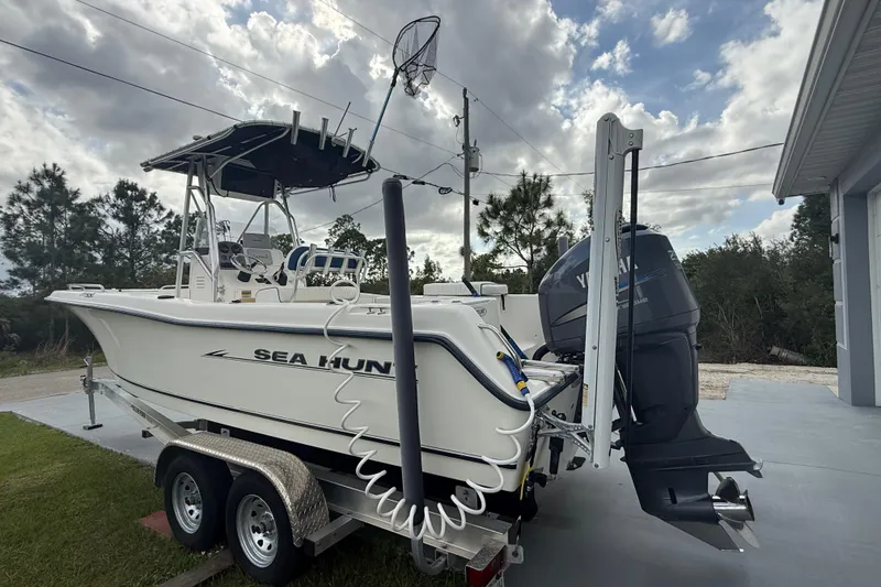 Slide: The Image of 2005 Sea Hunt Triton 232 boat with Yamaha 250 engine, parked near a modern house. - 4