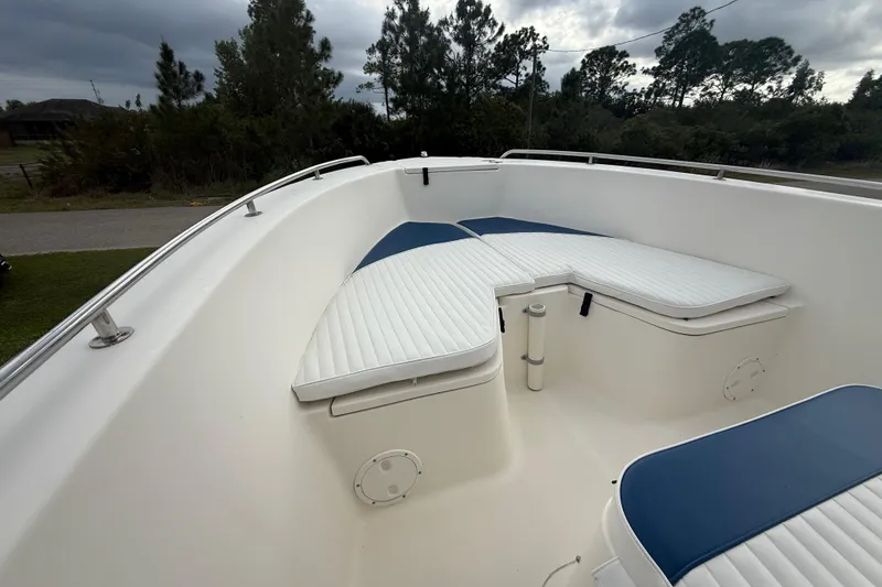 Slide: The Image of 2005 Sea Hunt Triton 232 boat with T-top, parked near a modern house. - 46