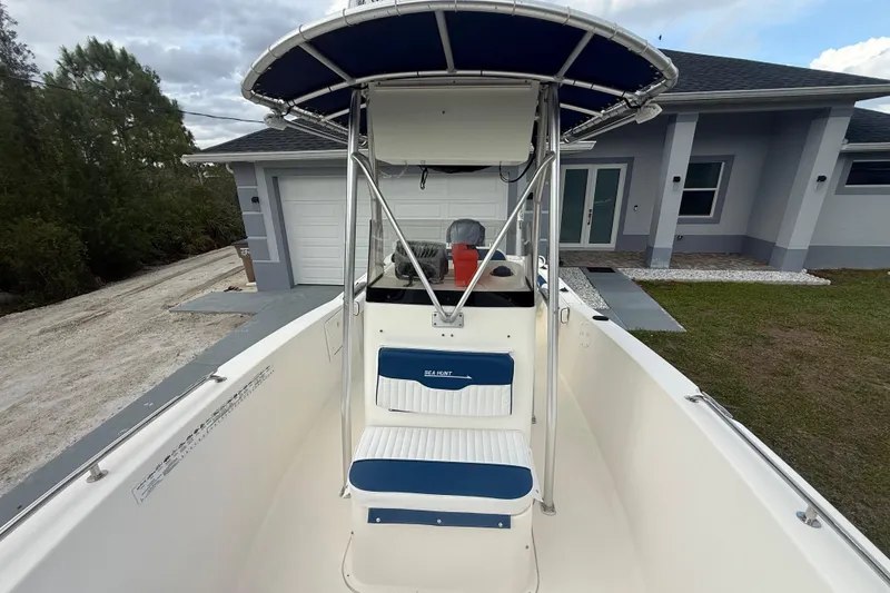 Slide: The Image of 2005 Sea Hunt Triton 232 boat with blue and white seating, parked near a modern house. - 47