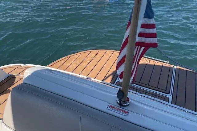 Slide: The Image of 2003 Sea Ray 240 Sundeck boat with American flag on deck, floating on water. - 12