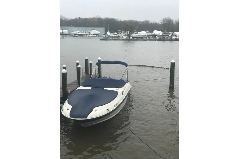 Slide: The Image of 2003 Sea Ray 240 Sundeck boat docked on a calm, overcast day. - 3