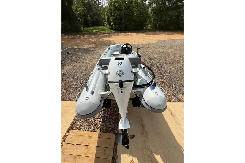 Slide: The Image of 2026 Highfield Classic 360 FCT inflatable boat with outboard motor, parked on gravel. - 7